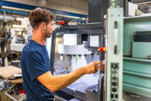 Man,using,mechanical,machine,to,mold,plastic,parts,in,a